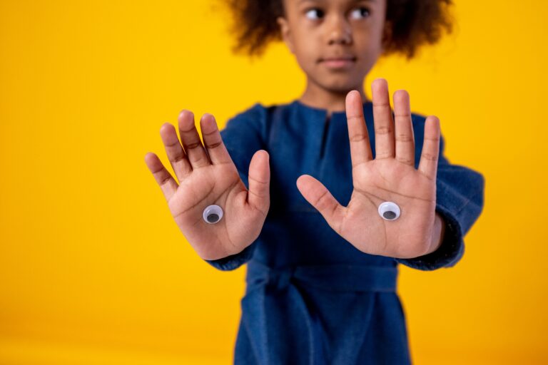 Photo d'une petite fille avec des autocollant d'oeil collés sur ses mains